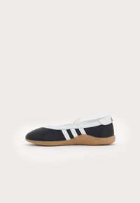 Black and white leather ballet flats with a round toe, featuring three white stripes, a white upper, and a tan rubber sole.