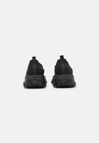 Black athletic sneakers with textured mesh upper, padded collar, and rubber outsole. Features prominent heel support and pull tab.