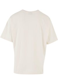 T-shirt à manches courtes en coton doux de couleur crème. Présente un col rond et une coupe décontractée. Texture lisse, sans motifs visibles.