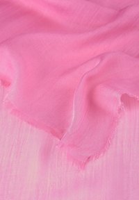 Écharpe rose clair avec une texture légère et transparente. Les bords sont effilochés, créant une finition délicate. Le tissu semble léger et fluide.