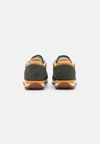 Grønne semskede sneakers med oransje detaljer, hvit logo bak, og brun gummisåle; lav toppdesign med teksturert finish.