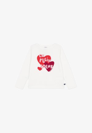 Wit shirt met lange mouwen met drie rode en paarse harten en roze tekst "EN PLEIN COEUR" op de voorkant.