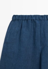 Pantalon bleu foncé à taille élastique avec poches latérales, en tissu texturé.
