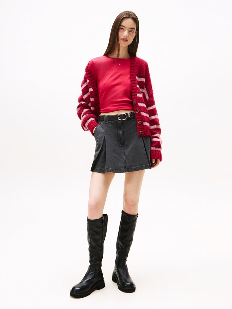 Cardigan rayé rouge et blanc, haut ajusté rouge, mini-jupe en denim noir, et bottes noires jusqu'aux genoux. Texture lisse, design décontracté.