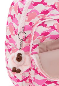 Růžový látkový batoh s vlnkovým vzorem, stříbrnými detaily a huňatým klíčenkou opice na zipu.