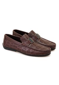 Braune Leder-Treilschuhe mit einem Krokodil-Muster, akzentuiert mit dekorativen Beschlägen und Kontrastnähten. Flache Sohle mit glatter Oberfläche.