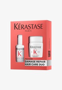 Kérastase haarverzorgingsduo in een rode doos met een witte pot en een kleine fles, gelabeld "Damage Repair," met zwarte tekst en een QR-code.