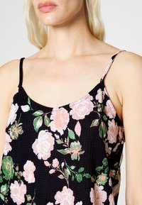 Top sem mangas preto com um padrão floral em rosa e verde. Tecido texturizado com decote arredondado e alças finas ajustáveis.