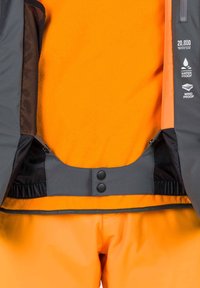 Wasserdichte, winddichte graue Jacke mit orangen Akzenten, ausgestattet mit Druckknopfverschlüssen und einem gerafften Bund über einer leuchtend orangefarbenen Fleece-Schicht.