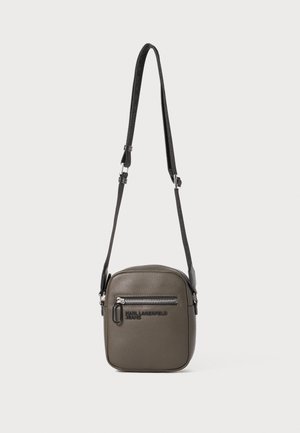 Borsa a tracolla quadrata verde oliva in finta pelle, con una tasca frontale con zip e una stampa del logo, dotata di tracolla regolabile.