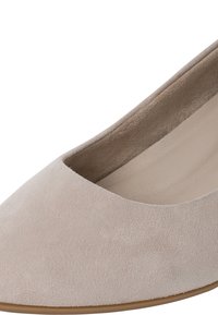 Zapato de tacón de ante beige con punta redondeada y diseño bajo. Textura suave con un forro interior ligeramente más oscuro y suela de goma delgada.