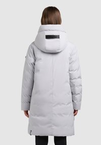 Gaiši pelēka pūkaina virsjaka ar lielu, polsterētu kapuci un melnu uzlīmi aizmugurē. Gluda tekstūra, ceļgala garuma, ar viegli sašaurinātu piegriezumu.