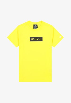 T-shirt jaune vif à manches courtes avec un patch logo rectangulaire noir affichant « Champion » en écriture jaune sur la poitrine.
