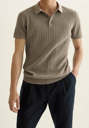 Polo en maille à manches courtes de couleur marron clair avec un motif torsadé texturé, col à revers et ourlet côtelé. Porté avec un pantalon foncé.