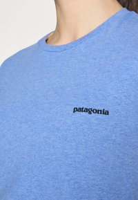 Mėlynas medvilninis marškinėliais su apvaliu iškirpimu. Juodas "patagonia" logotipas, esantis kairėje krūtinės pusėje. Lygus audinys su laisvu pritaikymu.