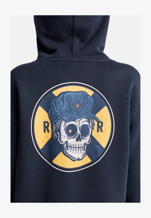 Marineblauer Hoodie mit einer großen Grafik eines Totenschädels mit blauer Mütze, rotem Auge und gelbem Hintergrund, eingefasst von einem kreisförmigen Design.
