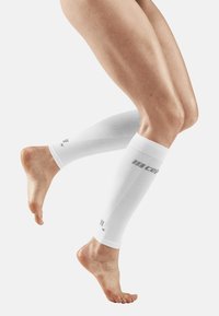 White compression leg sleeves with textured pattern and logo detail, fitted above the ankles, covering lower legs, with a smooth finish.