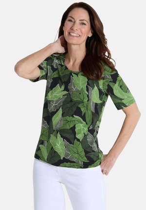 T-shirt noir à manches courtes avec un motif de feuilles vertes, col rond et en tissu doux et respirant. Associé à un pantalon blanc.