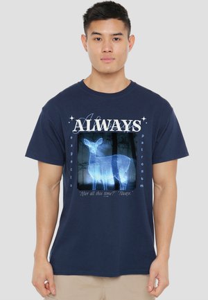 Young man wearing navy blue shirt with glowing deer graphic and text "Always," "Expecto Patronum," and "After all this time? Always."