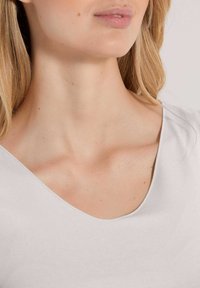 Lichtgrijze v-hals top met een zachte textuur en een ontspannen pasvorm, met een subtiele glans en een ronde halslijn.