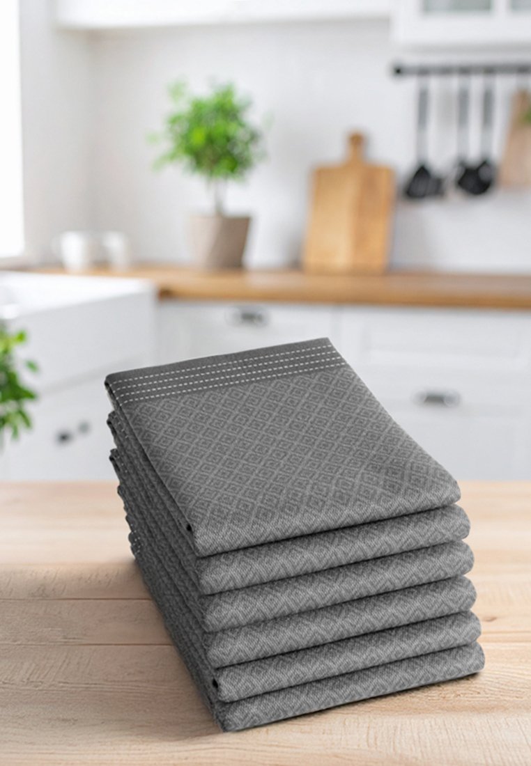 Pila de siete paños de cocina grises con un patrón de diamantes, rematados con costuras blancas a lo largo del borde superior. Tela suave, ordenadamente plegada.