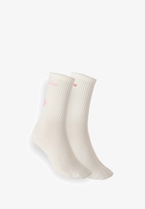 Chaussettes blanches en coton avec texture côtelée, ornées d'un texte rose et d'un motif en forme de cœur sur le côté extérieur. Longueur courte au niveau de la cheville.