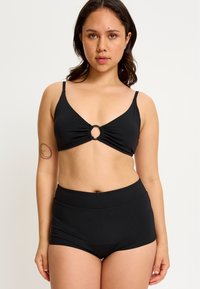 Ensemble de bikini noir comprenant un haut triangle avec un détail en anneau central et un tissu froncé, associé à un short taille haute. Texture lisse.