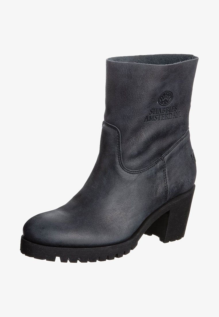 Bottine en cuir noir avec une finition lisse et un talon carré. Présente un bout arrondi et un logo embossé sur le côté. Semelle en caoutchouc texturée.