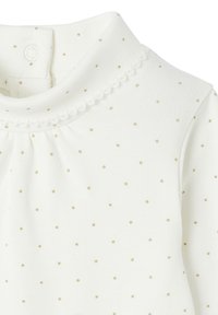 White fabric top with small gold polka dots, featuring a high neckline and a lace trim. Two snap closures at the back of the neck.