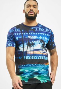 Trumpas rankovės grafikos marškinėliai su mėlynu tropiniu saulėlydžio dizainu, palmėmis, geometriniais raštais ir užrašu "JUST RHYSE VACATION VIBES."