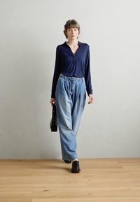 Mornarica s dugim rukavima, rastezljive svijetloplave traperice, crne cipele i crna torba. Glatka tkanina s minimalističkim dizajnom i visokom strukom.