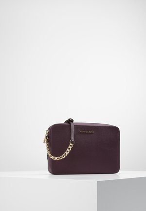 Sac à main rectangulaire en cuir violet foncé avec bandoulière chaîne dorée et logo Michael Kors, placé sur un socle blanc sur fond uni.