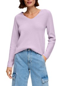 Lichtpaarse gebreide trui met een V-hals, geribbelde textuur en lange mouwen, gecombineerd met high-waisted blauwe denim cargobroeken.