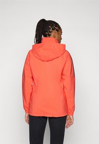 Koraalwaterdichte jas met een capuchon, elastische manchetten en een ontspannen pasvorm. Kenmerkt zwarte accenten op de mouwen en de rug voor contrast.