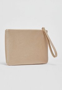 Pochette en or métallisé avec une texture lisse, une forme rectangulaire, une fermeture éclair et une anse amovible pour poignet.