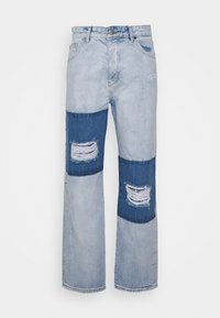 Jeans de mezclilla azul claro con dos parches en las rodillas de un azul más oscuro, con detalles desgastados. Diseño de pierna recta con cierre de botón.