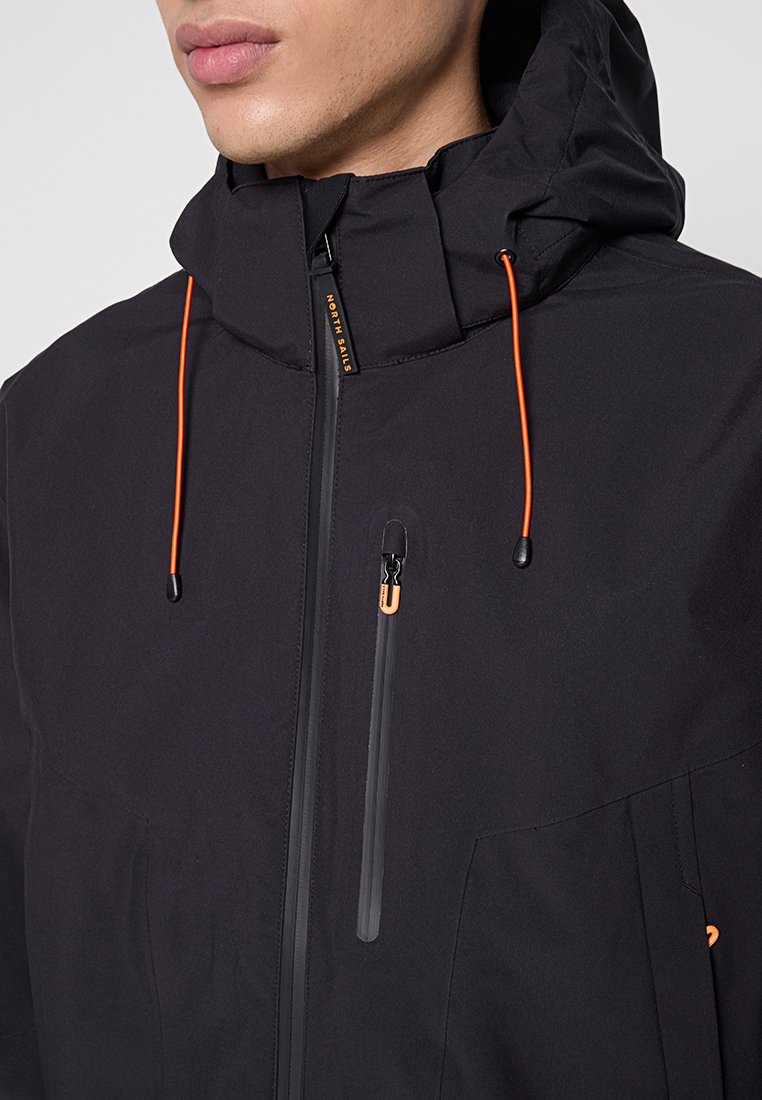 Giacca nera con cappuccio, dotata di lacci di colore arancione, tasca sul petto con zip impermeabile e tessuto texturizzato.