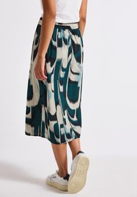 Ein knielanger Rock mit einem abstrakten Muster in Türkis, Creme und Schwarz. Hergestellt aus leichtem Stoff mit einem elastischen Bund.