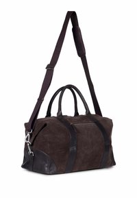 Brun nappa duffelbag med lærdetaljer, doble topphåndtak, avtakbar skulderrem og liten utvendig glidelås-lomme.
