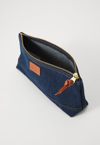 Denim-pose med gullglidelås, brunt lærdetalj og innvendig fôr. Rektangulær form med synlig sømdetalj.