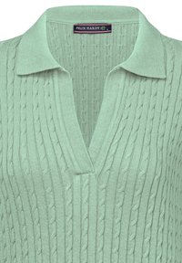Pull en polo tricoté vert clair avec un col en V, présentant un motif en relief en câble et un col. L'étiquette indique "FELIX HARDY."