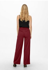 Rode wijde broek met elastische tailleband, gecombineerd met een zwart mouwloos topje. Gladde textuur, minimalistisch ontwerp en geen zichtbare patronen.