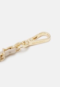 Gold-tone metal keychain featuring a clasp and a smooth beige leather accent. Includes textured hardware with engraved logo detail.