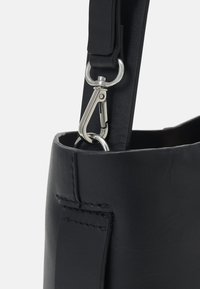 Borsa a tracolla in pelle nera con clip e tracolla in metallo argento, caratterizzata da una texture liscia e cuciture ordinate sui bordi.