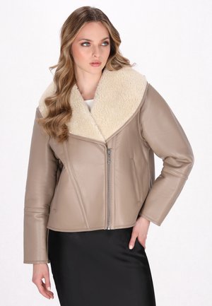 Giacca in pelle beige con un ampio colletto in shearling crema, chiusura con zip e maniche lunghe, caratterizzata da una silhouette aderente e una texture liscia.