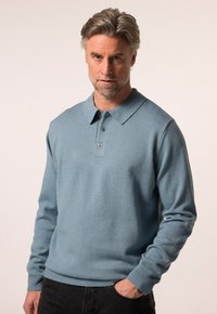 Jasnoniebieska longsleeve polo wykonana z dzianiny, z kołnierzykiem i zapięciem na trzy guziki. Rękawy i dół z prążkowanym wykończeniem.