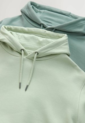 Duos švelnių žalių atspalvių džemperiai, vienas šviesus, kitas tamsesnis. Ypatybės apima virvutės su metaliniais galiukais ir lygų paviršių.