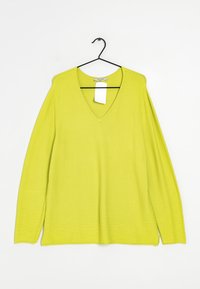 Limegrüner V-Ausschnitt-Pullover mit langen Ärmeln, gerippter Textur und geradem Saum. Hängt an einem schwarzen Metallhaken, mit angehängtem Markenetikett.