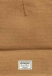 Bonnet en tricot beige avec un revers, portant une étiquette rectangulaire avec la marque "ZIGZAG ACTIVE LIFESTYLE". Tissu texturé.