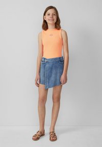 Neon oranje mouwloze ribbed top met een zonontwerp, gecombineerd met een blauwe denim wikkelrok en bruine bandjes sandalen.
